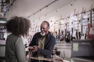 Senior male paying in a guitar store with credit card
