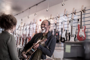 Senior male playing guitar in store