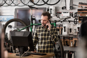 Small business owner on phone and computer in a store
