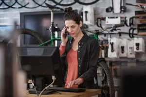 Small business owner on phone and computer in a store