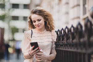 Young adult female looking at smartphone outdoors in city
