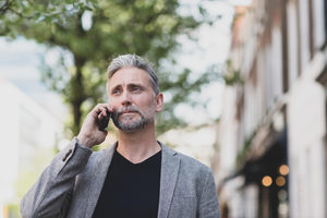 Mature male walking and on smartphone in city