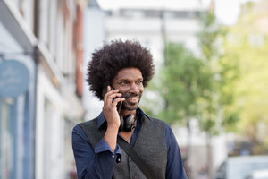 African American male walking and on on smartphone in city