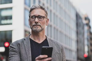 Mature male walking and on on smartphone in city