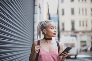 Young adult female walking and holding smartphone