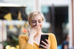 Young adult female laughing at smartphone