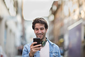 Young adult male laughing at smartphone