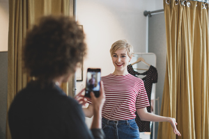 Young adult female trying on clothes in a vintage store with friend