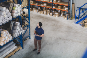 Overhead shot of male working in distribution warehouse with digital tablet