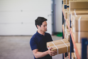 Male picking up box from shelf in distribution warehouse