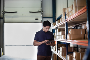 Male working in distribution warehouse with digital tablet