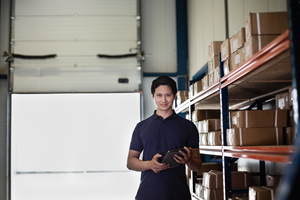 Portrait of male working in distribution warehouse with digital tablet