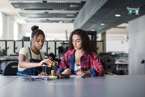 High school students working on a robotic arm in class