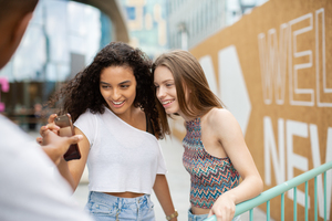 Teenagers socialising outdoors in city looking at smartphone