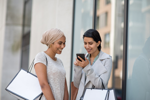 Muslim friends using a smartphone on a shopping trip