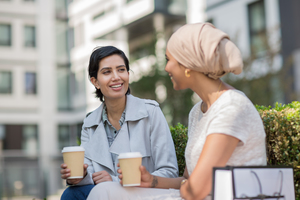 Female Arabic friends having coffee together outdoors