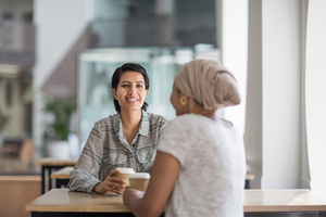 Female Muslim co-workers having coffee together