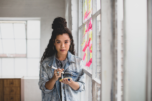 Portrait of young adult female brainstorming in a creative office with adhesive notes