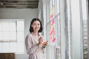 Portrait of young adult female brainstorming in a creative office with adhesive notes