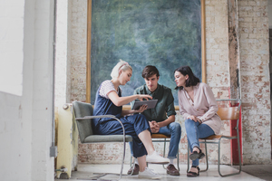 Young adults in a meeting in a creative studio with a digital tablet