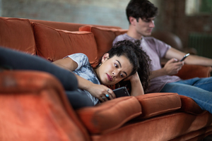Millennials using smartphones relaxing on sofa