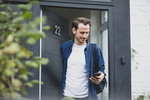 Adult male leaving the house and checking smartphone