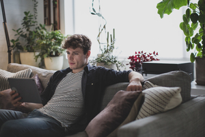 Young adult male watching video on digital tablet