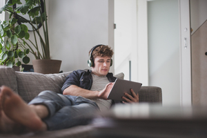 Young adult male watching video on digital tablet