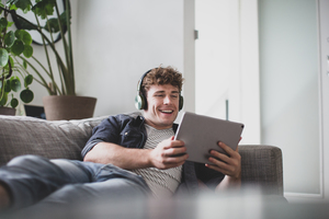 Young adult male watching video on digital tablet