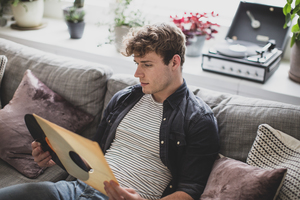 Young adult male looking at vinyl record