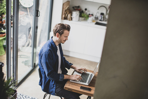 High angle shot of adult male working from home in kitchen