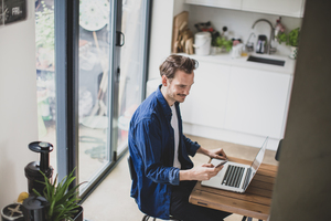 High angle shot of adult male working from home in kitchen