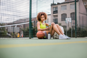 Young adult female on a basketball court using smartphone