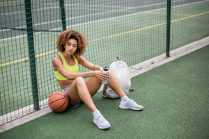 Young adult female sitting on a basketball court