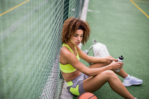Young adult female sitting on a basketball court