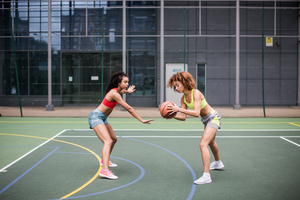 Young adult females playing basketball