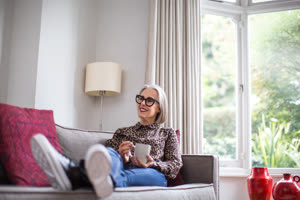 Mature adult female relaxing at home with a hot drink