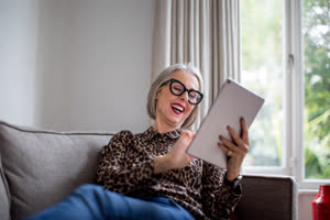 Mature adult female laughing with a digital tablet