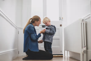 Mother helping child put on a coat