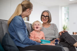 Boy opening a birthday present with grandmother and mother