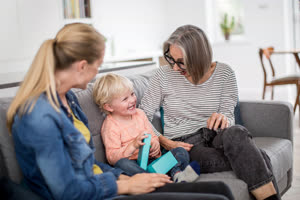 Boy opening a birthday present with grandmother and mother