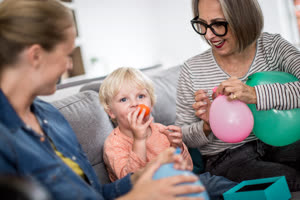 Boy blowing up birthday balloons with family