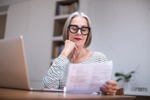 Mature adult female paying bill online using a laptop