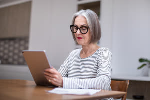 Mature adult female paying bill online using a digital tablet