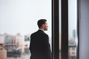 Businessman looking out at city skyline thinking