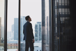 Businessman looking up at skyscraper thinking