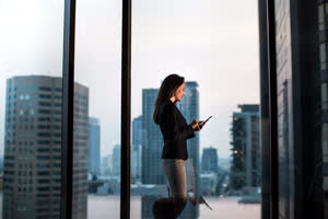 Businesswoman working late with city skyline in background
