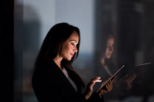 Businesswoman and reflection working late using digital tablet