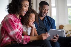 African American family watching video on digital tablet at home