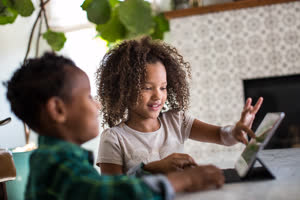 African American brother and sister playing together on digital tablet